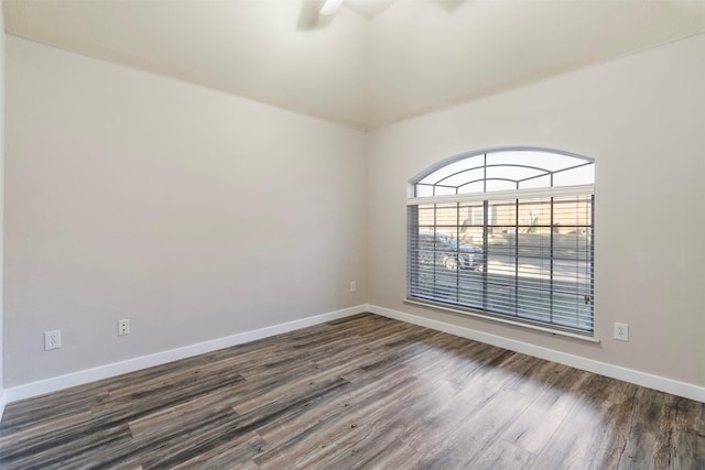 empty room featuring a ceiling fan, dark wood-type flooring, and baseboards