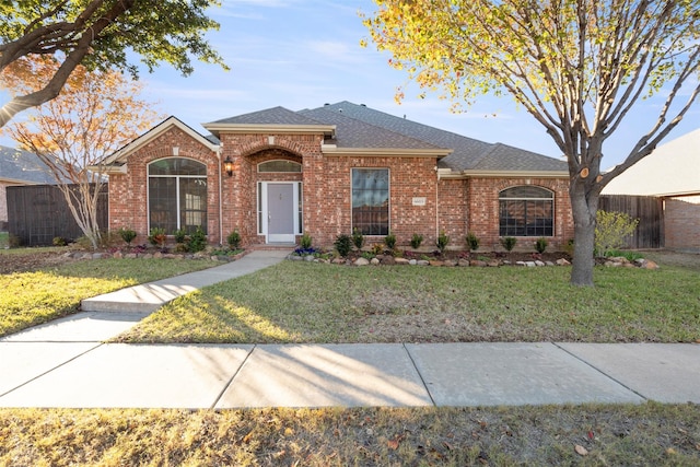 ranch-style house featuring brick siding, a front lawn, and fence