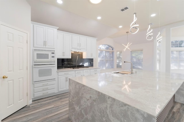 kitchen featuring white appliances, sink, pendant lighting, hardwood / wood-style flooring, and white cabinetry