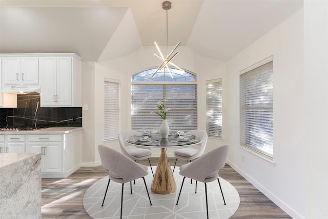 dining space featuring hardwood / wood-style floors and vaulted ceiling