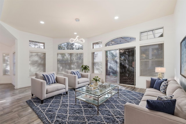 living area with recessed lighting, baseboards, an inviting chandelier, and wood finished floors