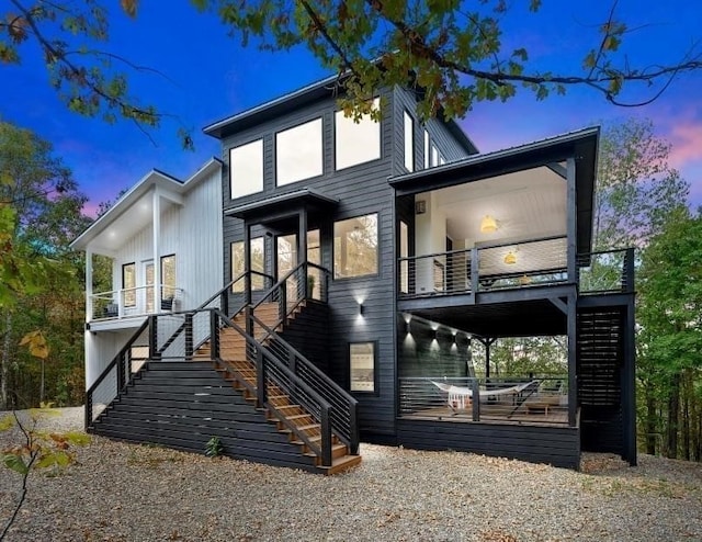 back house at dusk featuring a wooden deck