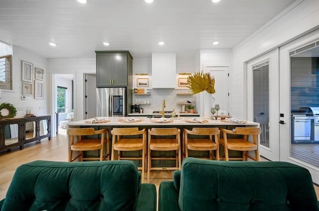 kitchen with french doors, a kitchen bar, gray cabinetry, stainless steel refrigerator, and light hardwood / wood-style floors