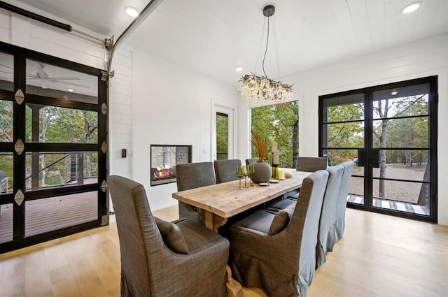 dining area featuring an inviting chandelier, a wealth of natural light, light hardwood / wood-style floors, and french doors