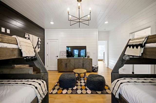 bedroom featuring an inviting chandelier, light hardwood / wood-style flooring, wooden ceiling, and wood walls