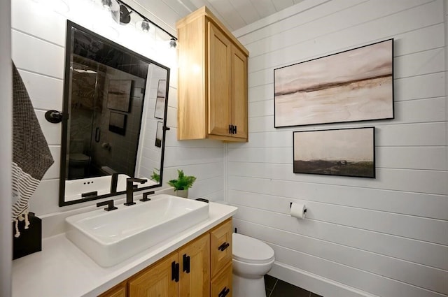 bathroom with vanity, toilet, walk in shower, and wooden walls