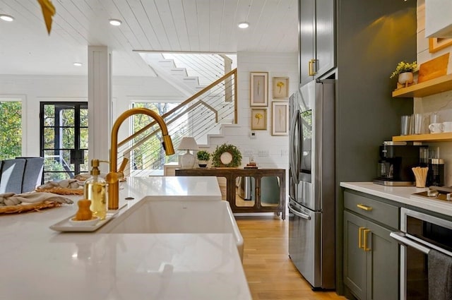 kitchen featuring gray cabinetry, wooden ceiling, appliances with stainless steel finishes, light stone countertops, and light hardwood / wood-style floors