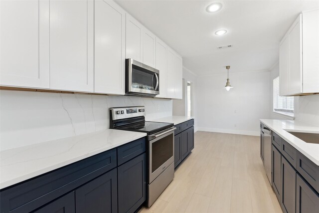 kitchen with light stone countertops, appliances with stainless steel finishes, decorative light fixtures, white cabinets, and light wood-type flooring