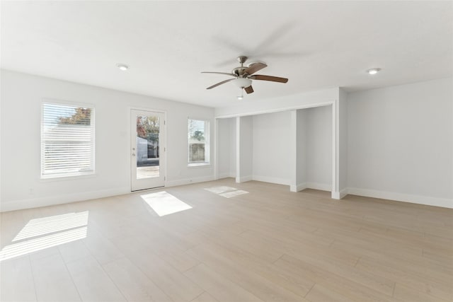 empty room with ceiling fan and light hardwood / wood-style flooring