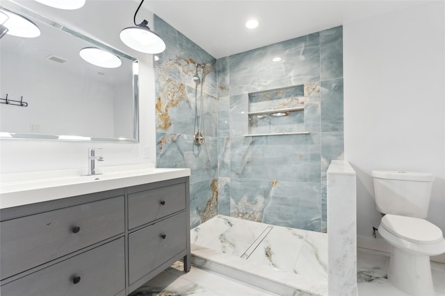 bathroom featuring tiled shower, vanity, and toilet