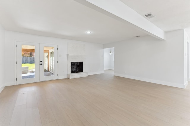 unfurnished living room with french doors, a fireplace, light hardwood / wood-style floors, and beamed ceiling