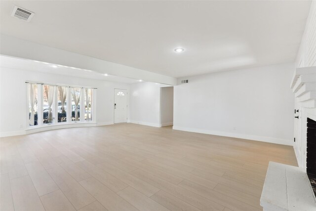 unfurnished living room featuring light hardwood / wood-style floors and a brick fireplace