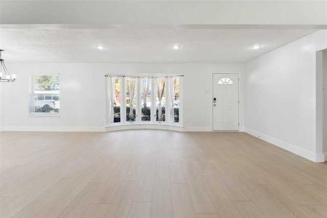 empty room with light hardwood / wood-style floors and a chandelier