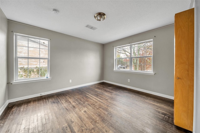 unfurnished room featuring a textured ceiling, dark hardwood / wood-style flooring, and plenty of natural light