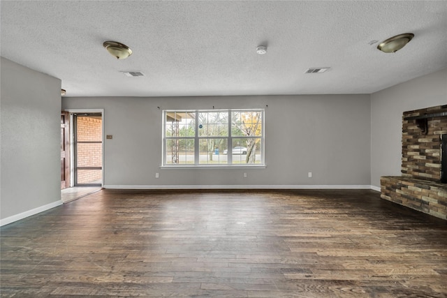 unfurnished living room with a textured ceiling, dark hardwood / wood-style floors, and a brick fireplace