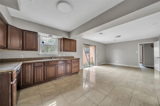 kitchen with dark brown cabinetry, light tile patterned floors, and sink