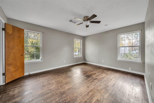 spare room with dark hardwood / wood-style flooring, a healthy amount of sunlight, and a textured ceiling