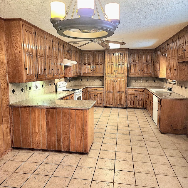 kitchen featuring kitchen peninsula, white appliances, tasteful backsplash, and light tile patterned flooring