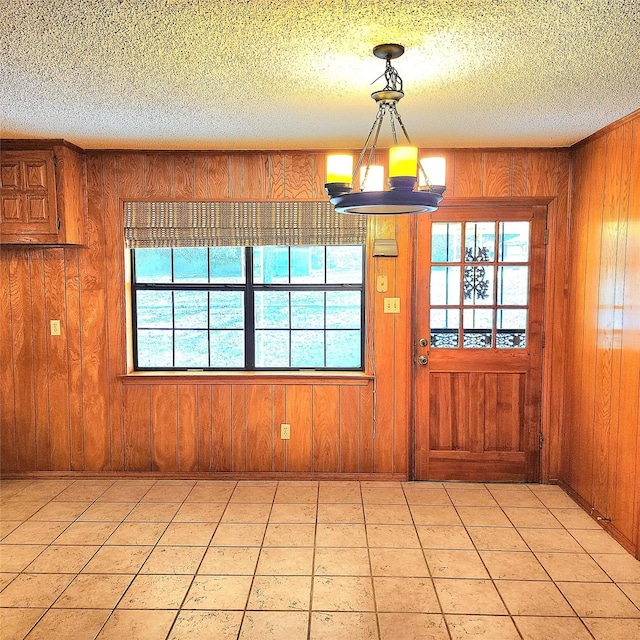 interior space featuring wood walls, light tile patterned flooring, and a textured ceiling