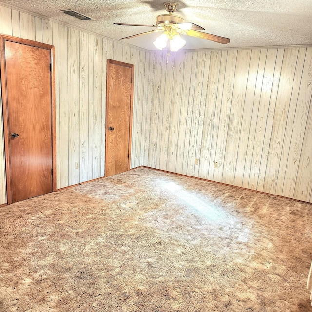 unfurnished room featuring a textured ceiling, carpet floors, and wood walls