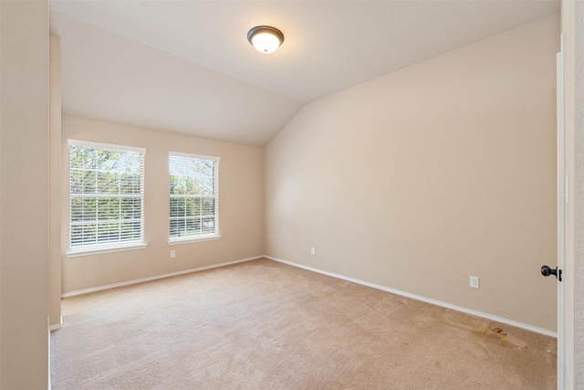 empty room with light colored carpet, baseboards, and lofted ceiling