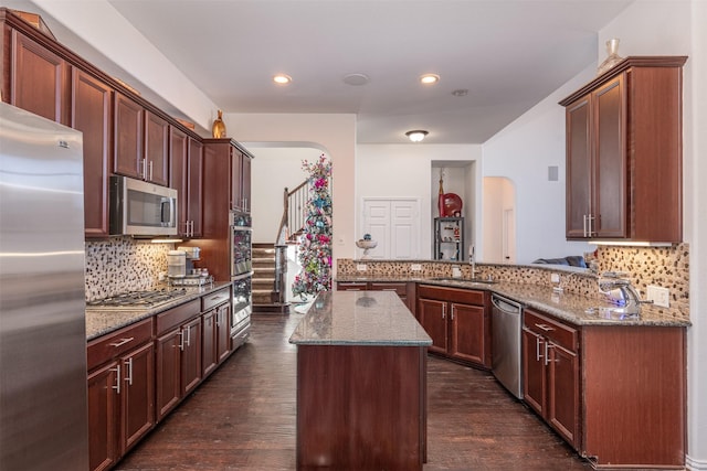 kitchen featuring kitchen peninsula, dark hardwood / wood-style flooring, stainless steel appliances, and sink