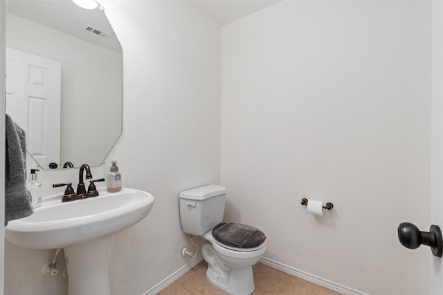 half bath with visible vents, baseboards, a sink, toilet, and tile patterned flooring