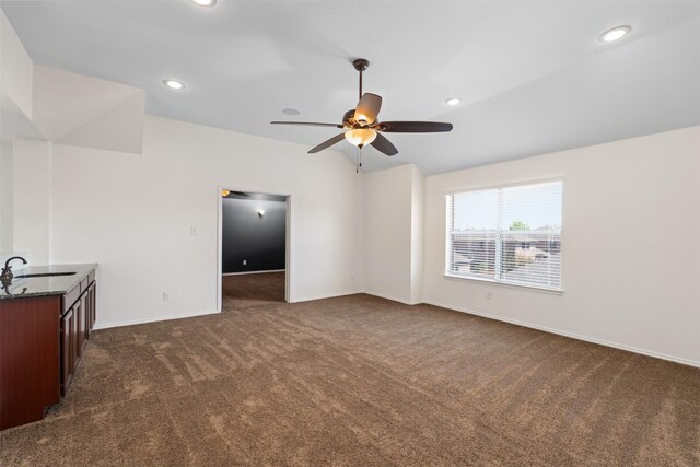unfurnished living room with dark colored carpet, vaulted ceiling, recessed lighting, ceiling fan, and a sink