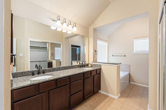 bathroom featuring a sink, tile patterned floors, vaulted ceiling, and a garden tub