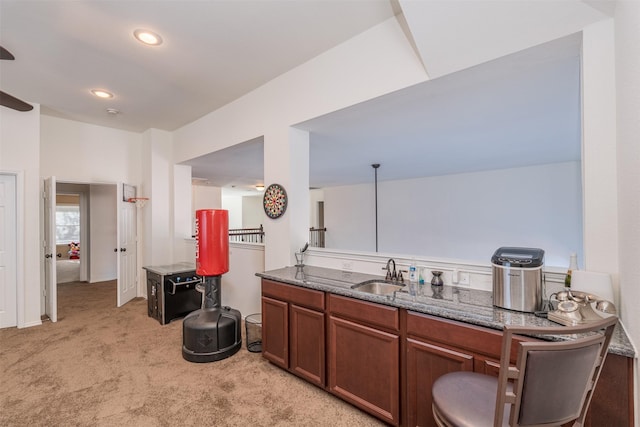 interior space with light carpet, decorative light fixtures, dark stone countertops, and sink