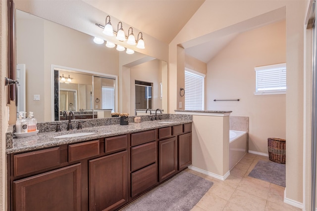 bathroom with tile patterned floors, vanity, a tub to relax in, and vaulted ceiling