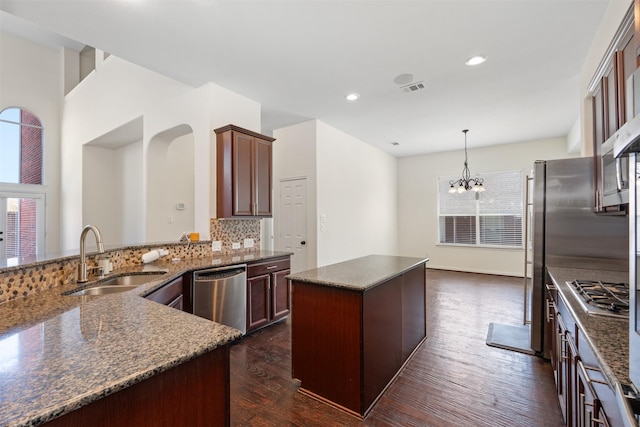 kitchen with backsplash, visible vents, dark wood finished floors, stainless steel appliances, and a sink