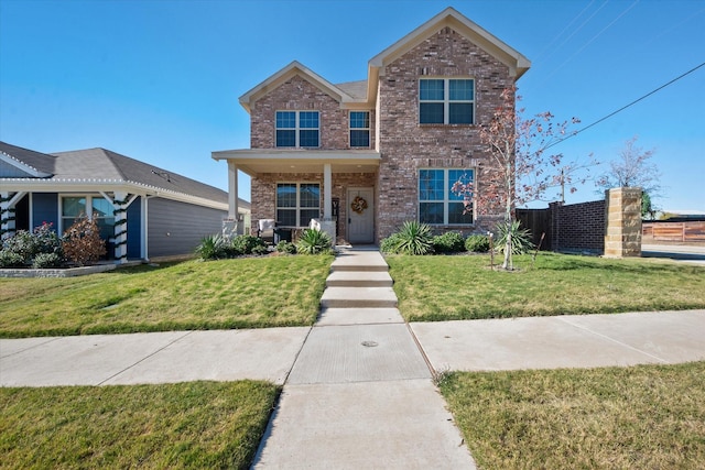 traditional-style home with fence, a front lawn, and brick siding