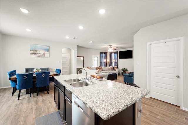 kitchen with arched walkways, recessed lighting, stainless steel dishwasher, wood tiled floor, and a sink