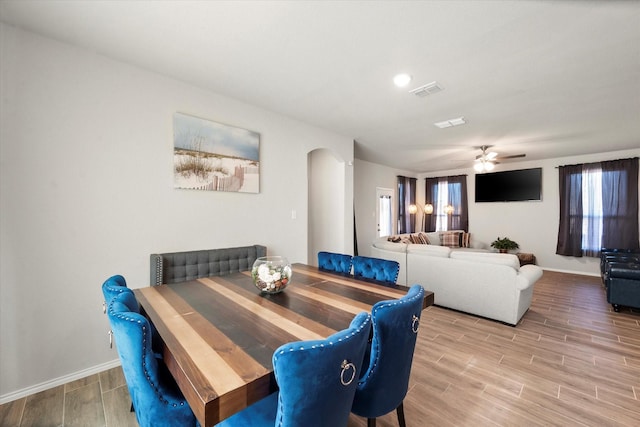 dining space with wood tiled floor, arched walkways, ceiling fan, and baseboards