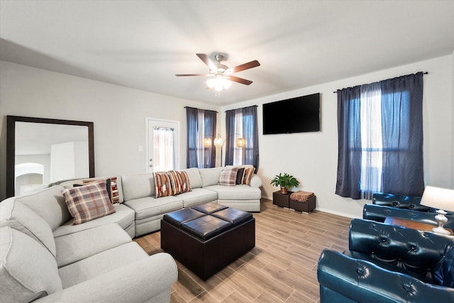 living room with light wood-type flooring, a healthy amount of sunlight, and a ceiling fan