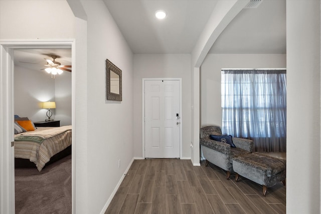 entryway featuring arched walkways, dark wood finished floors, and baseboards