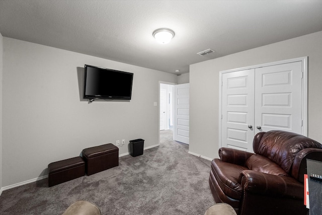 carpeted living area with visible vents, a textured ceiling, and baseboards