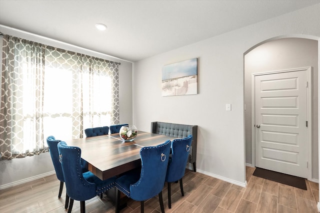 dining room featuring wood tiled floor, arched walkways, and baseboards