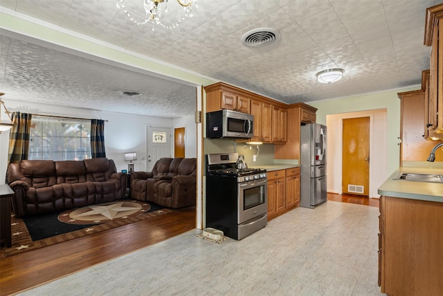 kitchen with sink, stainless steel appliances, light hardwood / wood-style floors, and a chandelier