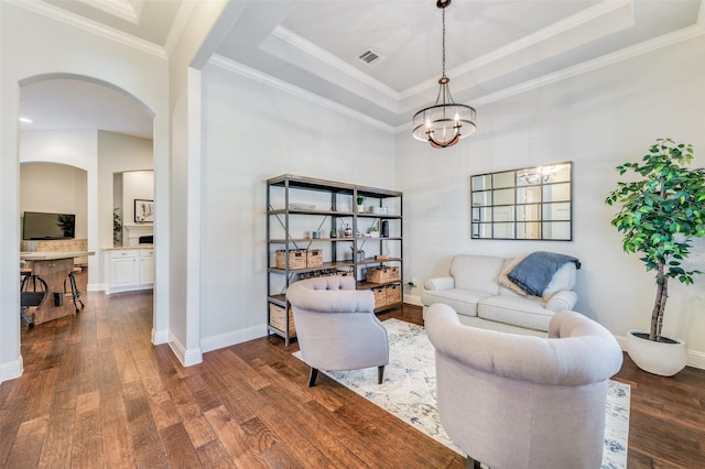 living room with a raised ceiling, crown molding, a chandelier, and dark hardwood / wood-style floors