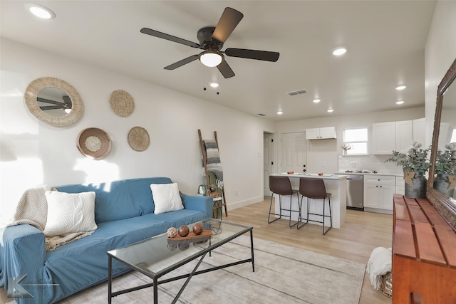 living room with ceiling fan and light hardwood / wood-style flooring