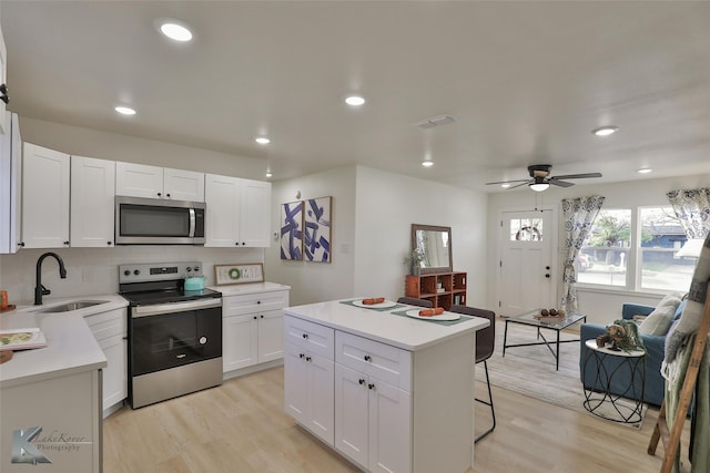 kitchen featuring white cabinets, appliances with stainless steel finishes, a kitchen island, and sink