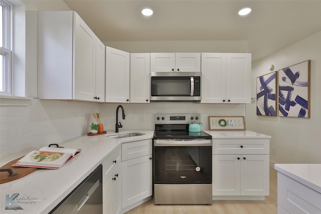 kitchen with white cabinetry, sink, stainless steel appliances, and light hardwood / wood-style flooring