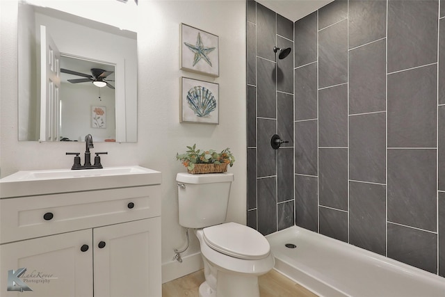 bathroom featuring hardwood / wood-style floors, vanity, ceiling fan, toilet, and a tile shower