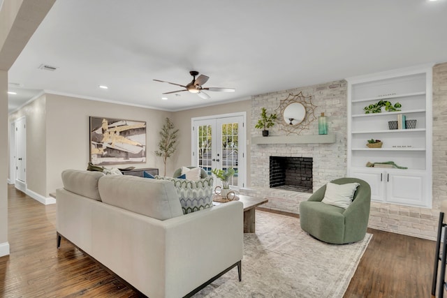 living room with crown molding, a brick fireplace, dark hardwood / wood-style floors, and french doors