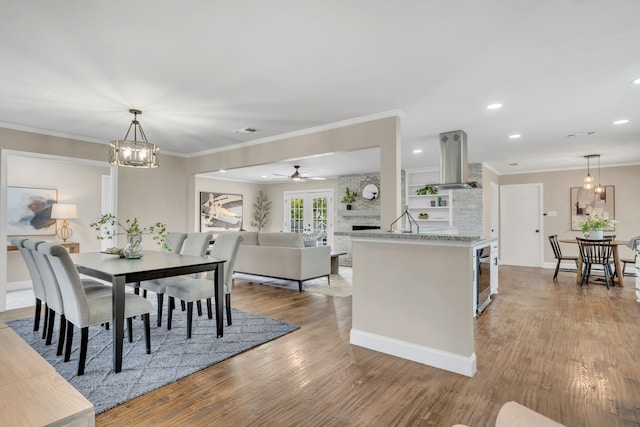 dining area with hardwood / wood-style flooring, ceiling fan with notable chandelier, and ornamental molding