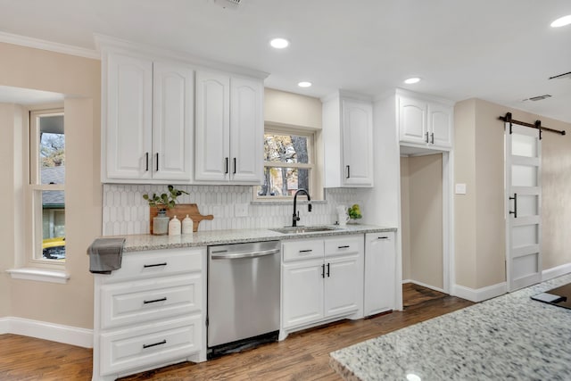 kitchen featuring sink, dishwasher, a barn door, light stone countertops, and white cabinets