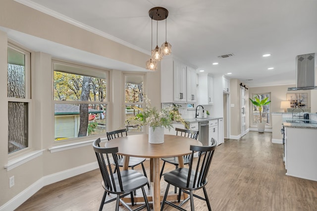 dining area featuring ornamental molding, sink, and light hardwood / wood-style flooring