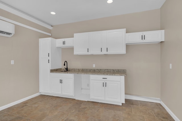 kitchen with white cabinets, light stone counters, and sink